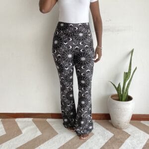 Black background white celestial sun moon star flare pants, front view